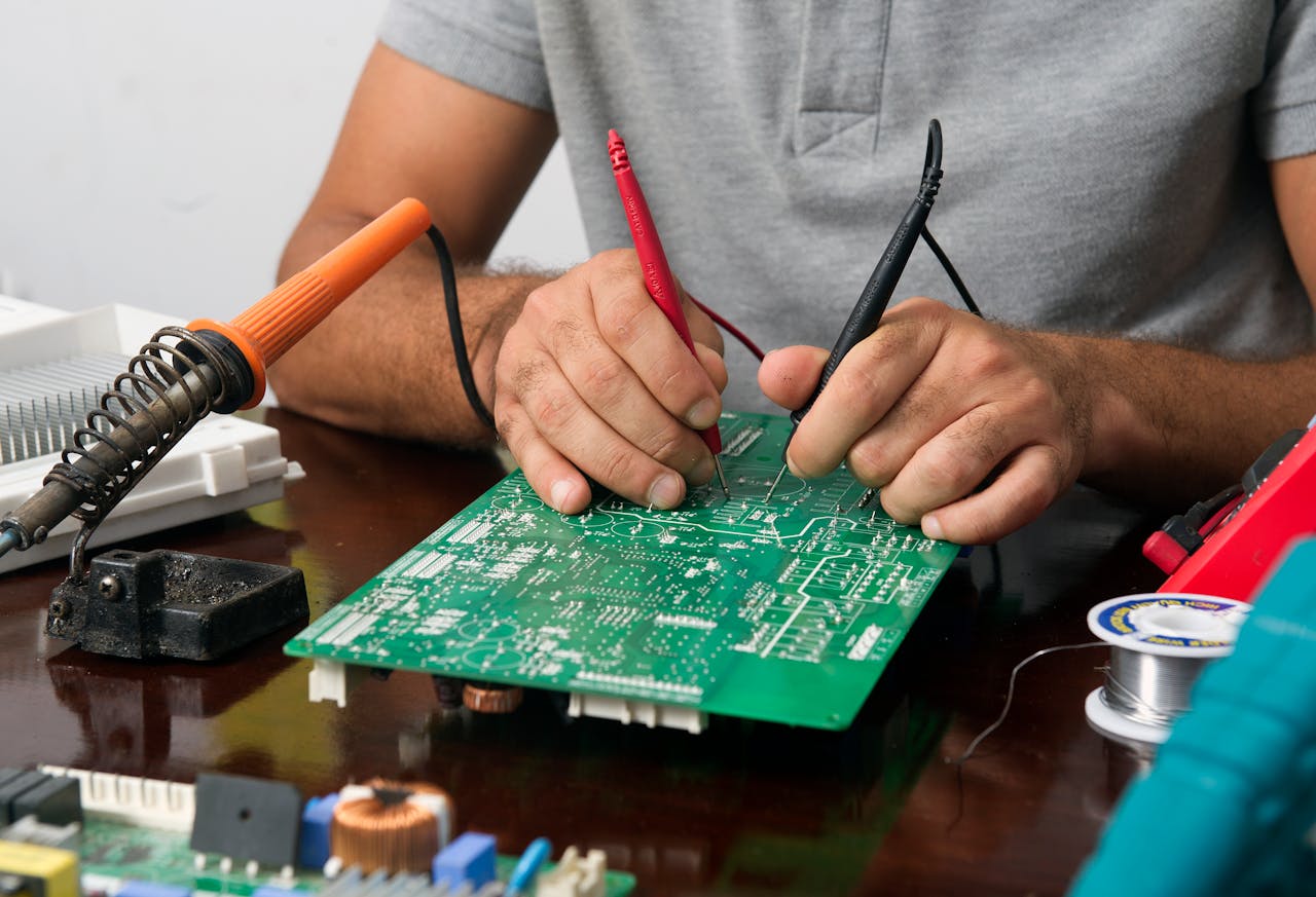 Close-up of a technician repairing an electronic circuit board with precision tools.