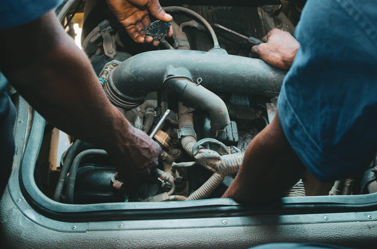 Auto mechanics repairing an engine in a Nigerian workshop. Close-up hands and tools.