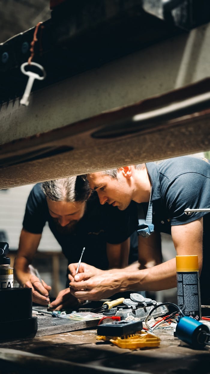 Two professionals focused on repairing machinery in a workshop setting with tools.